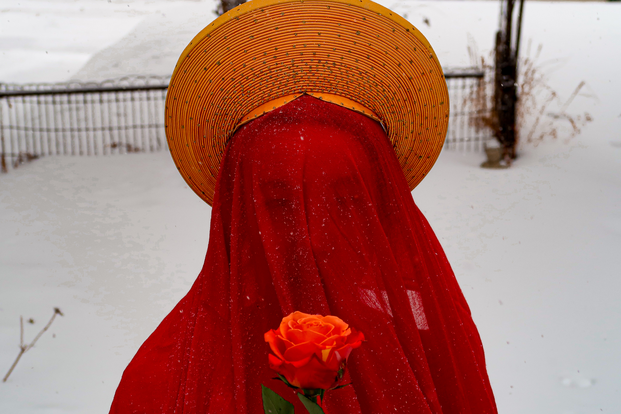 Sophia Terazawa performing in snow, veiled in red with a conical hat and rose. Photo by Callisto Moses.