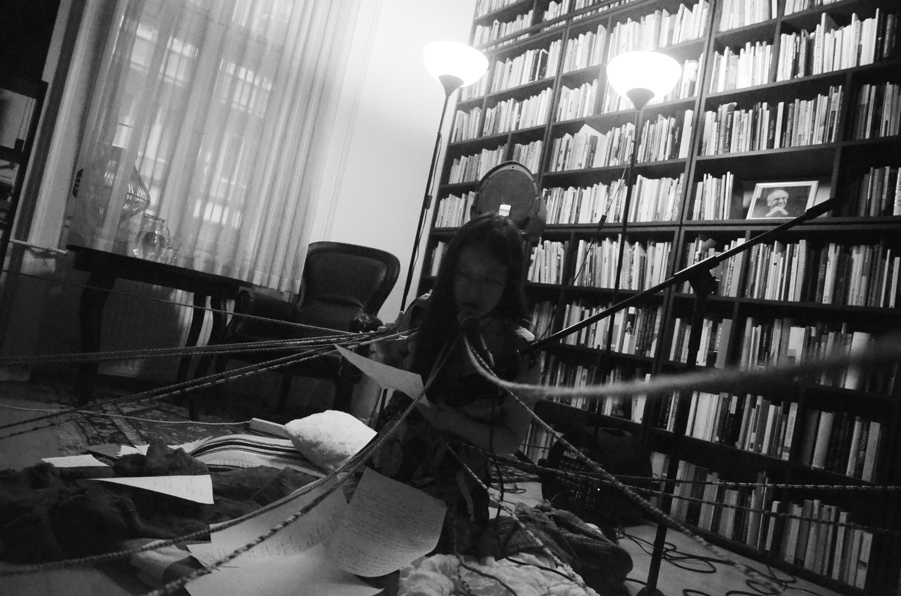 Sophia Terazawa performing at the Tomaž Šalamun Center, Ljubljana — entangled in rope and manuscript pages among shelves of books.